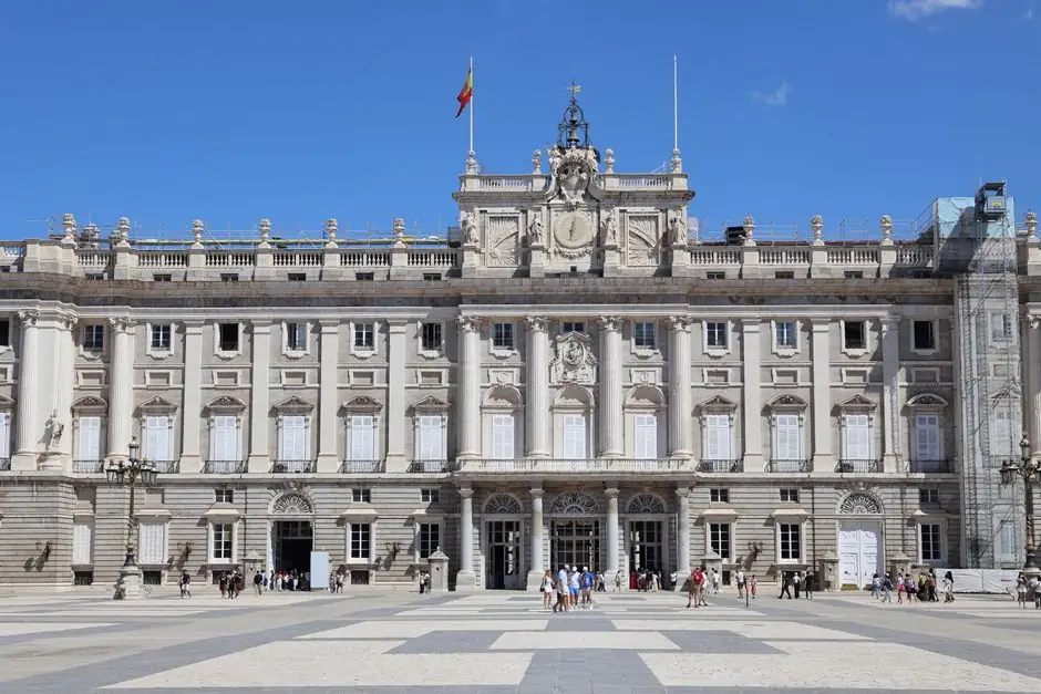 Un día despejado en el Palacio Real de Madrid con turistas en la plaza.