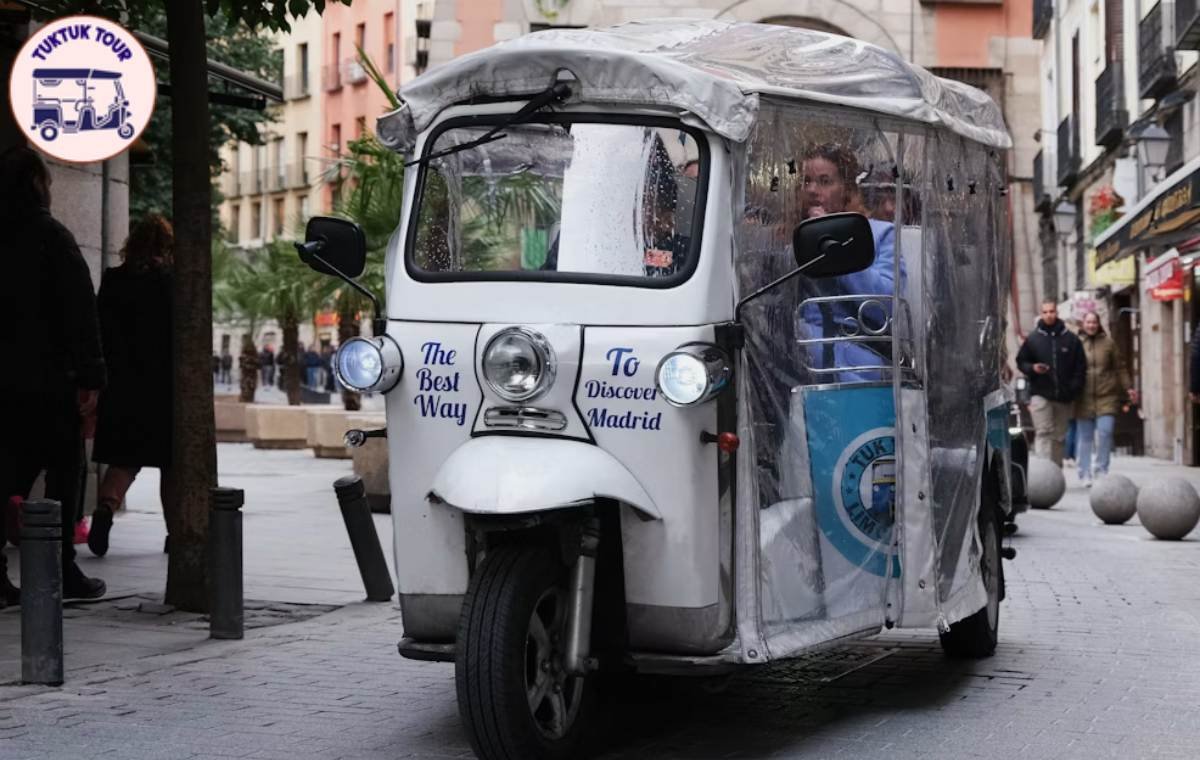 Tuk tuk eléctrico aparcado junto a un monumento de Madrid incluido en el tour Essentials de 2 horas
