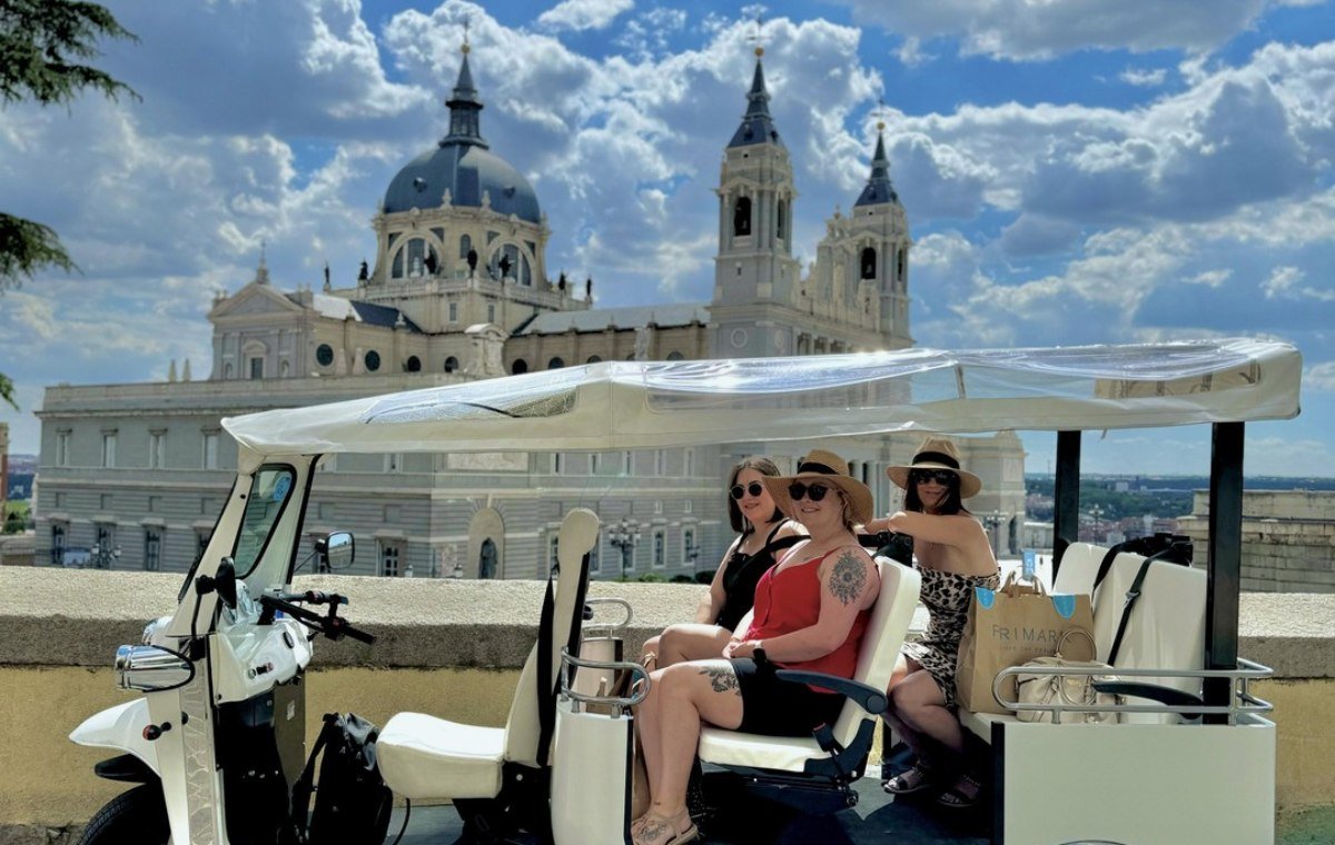 Tuk tuk driving through Madrid at sunset with the city skyline behind it