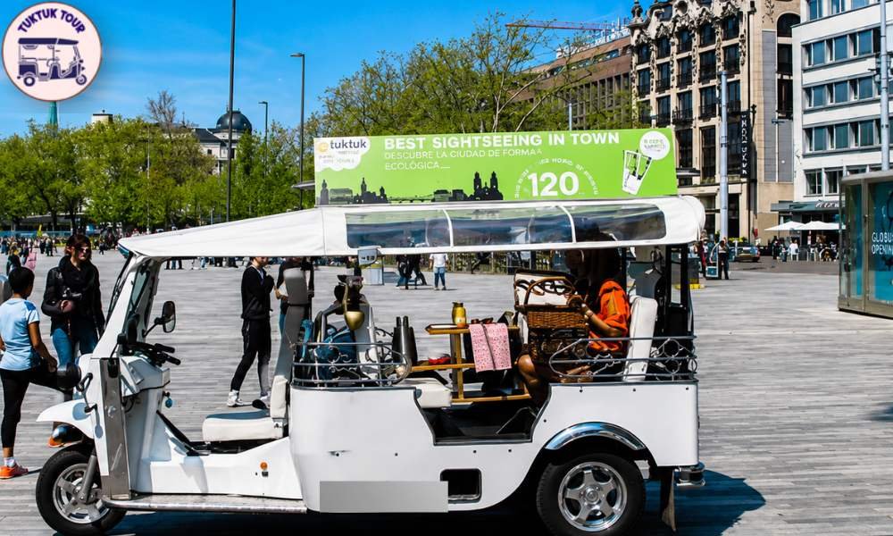 Una vibrante calle de Madrid con tuk tuks aparcados y colorida arquitectura europea.