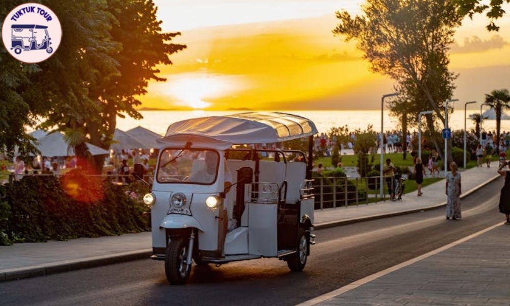 Tuk tuk circulando por Madrid al atardecer con el perfil de la ciudad de fondo