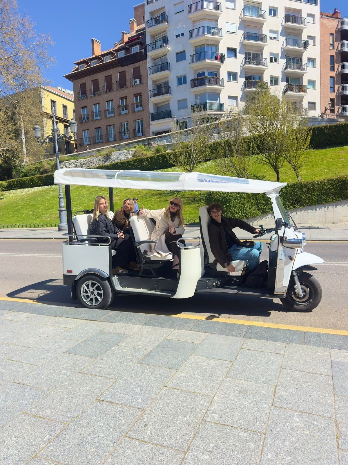 Una vibrante calle de Madrid con tuk tuks aparcados y colorida arquitectura.